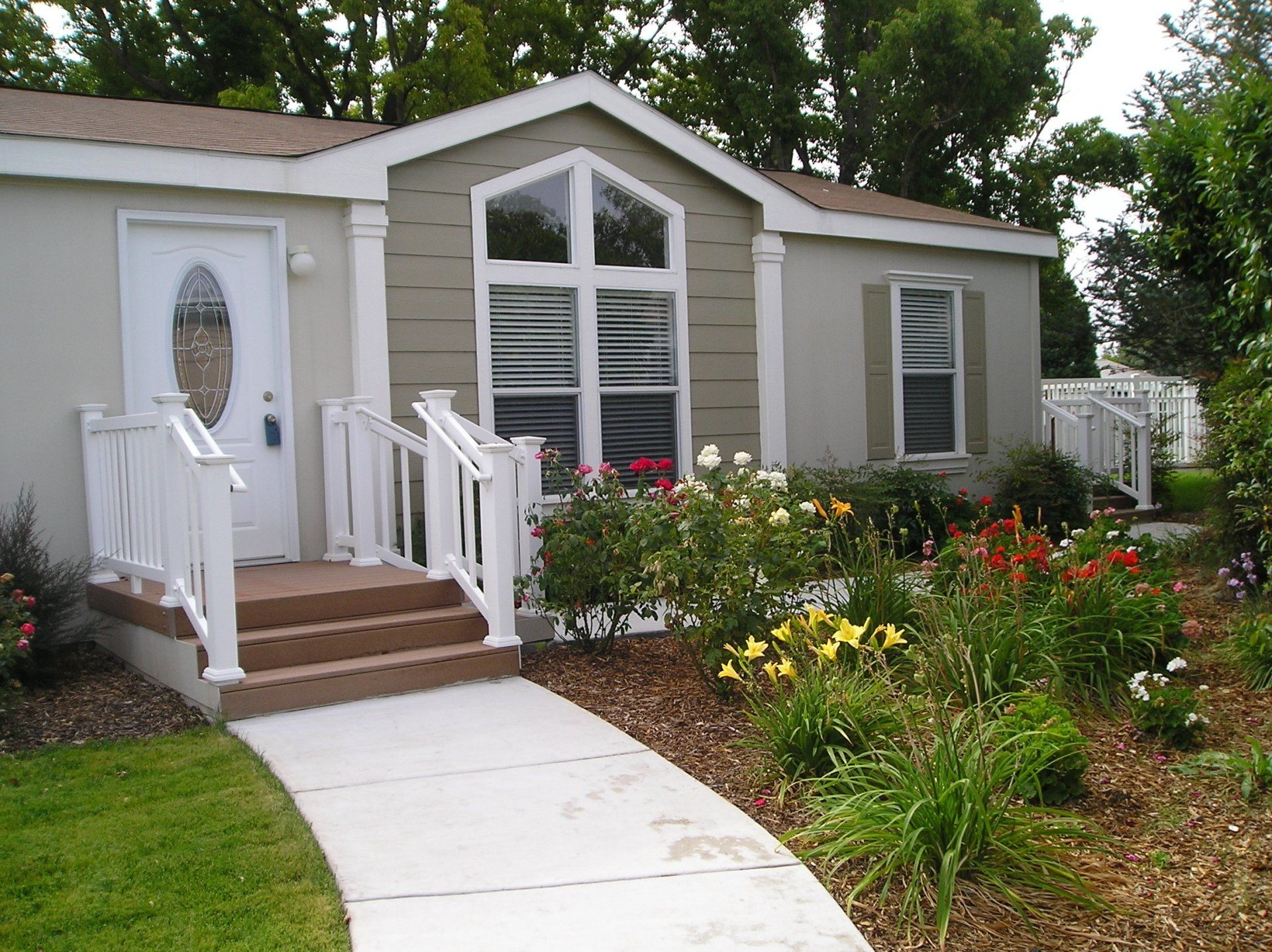 Image of Home in Moon Valley Community with Flower Garden on Lawn, Decorative Porch and Lead Glass Window on Front Door.