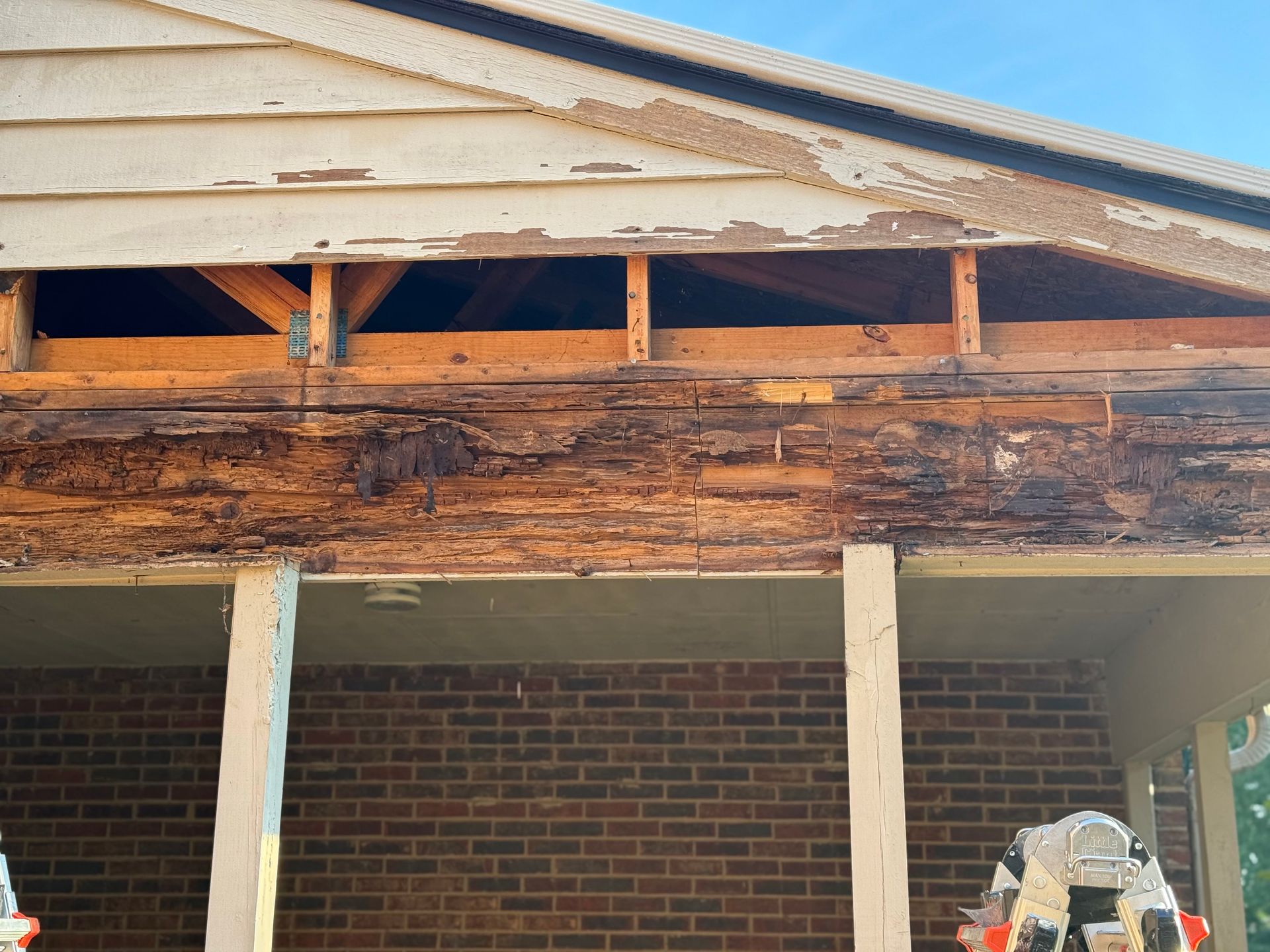 Partially demolished house exterior with exposed wooden framing and brick walls under a roofline