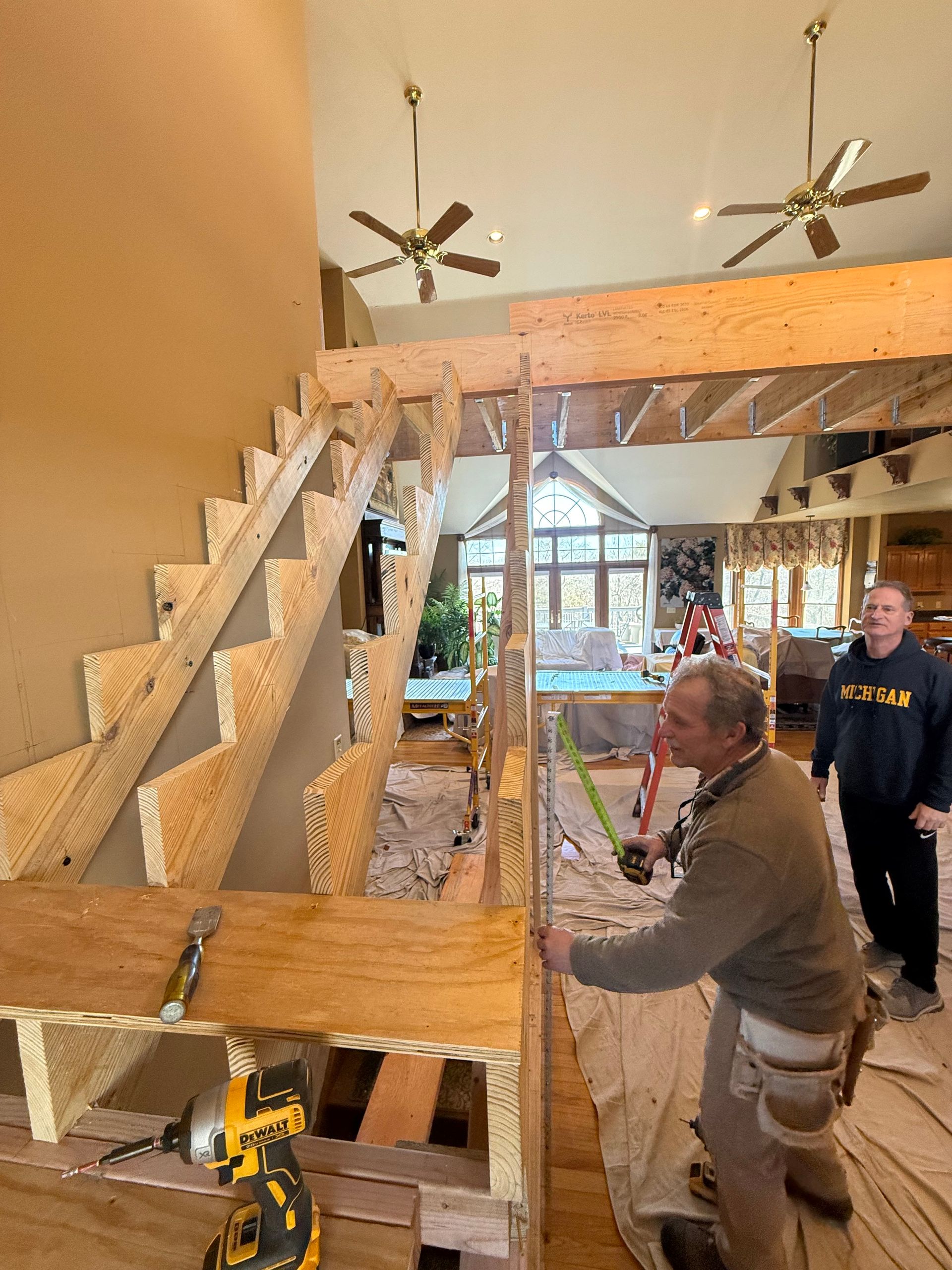 People working inside a large wooden staircase under construction in a bright room
