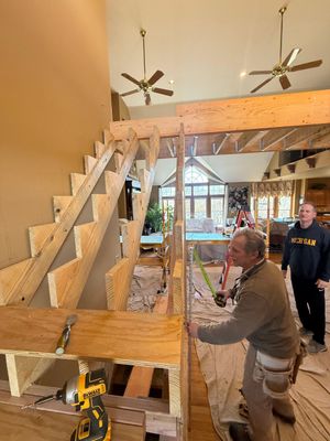 People working inside a large wooden staircase under construction in a bright room
