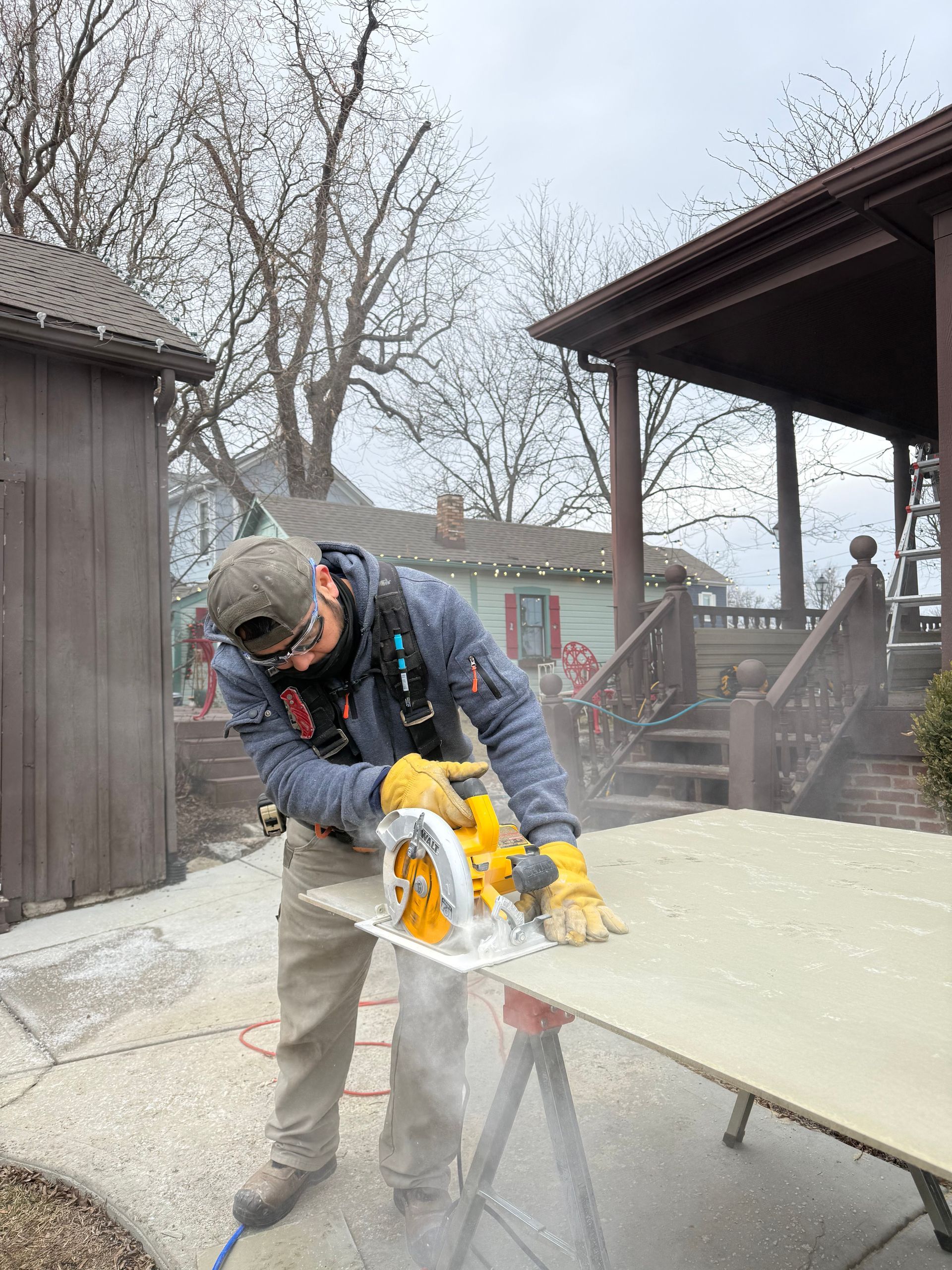 Worker using a circular saw to cut a board outdoors in a dusty yard