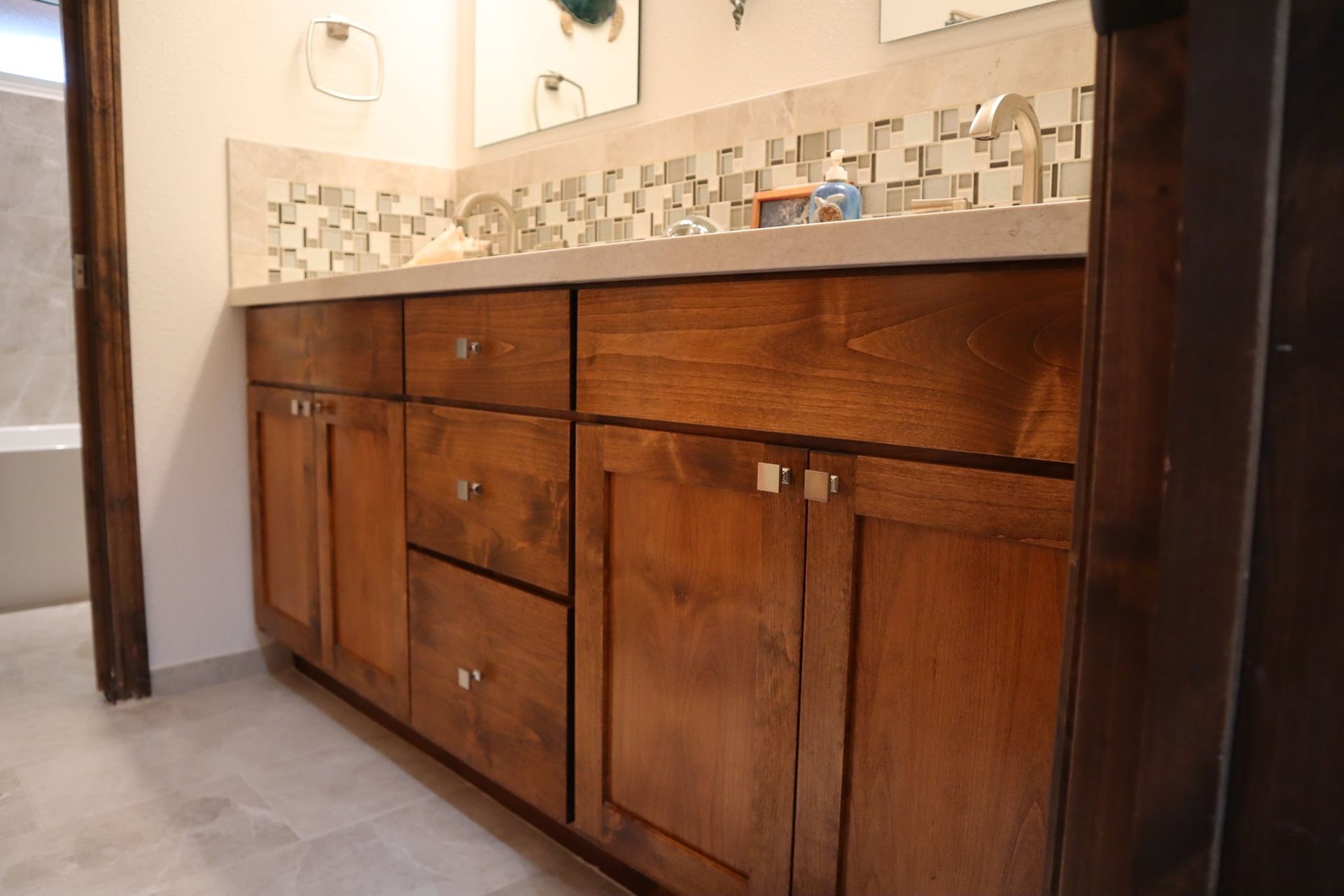 Bathroom vanity with dark wood cabinets, a light countertop, and decorative backsplash.
