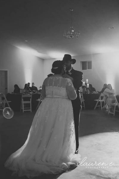 Couple slow dancing at a wedding reception in a decorated hall, bride in a long white gown