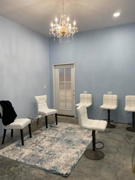 Small elegant room with white chairs, patterned rug, chandelier, and light blue walls