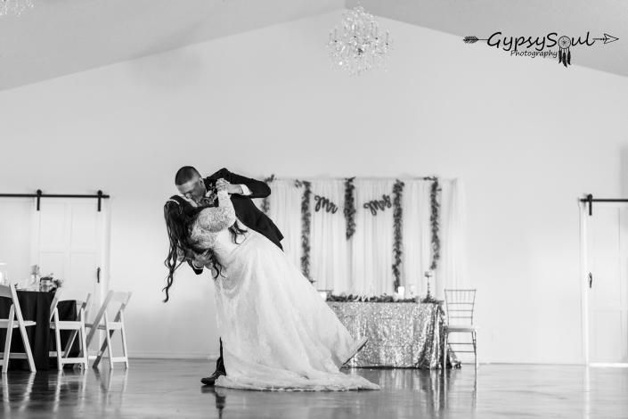 Bride and groom dancing in a bright reception hall, with the bride leaning back in a dramatic dip.