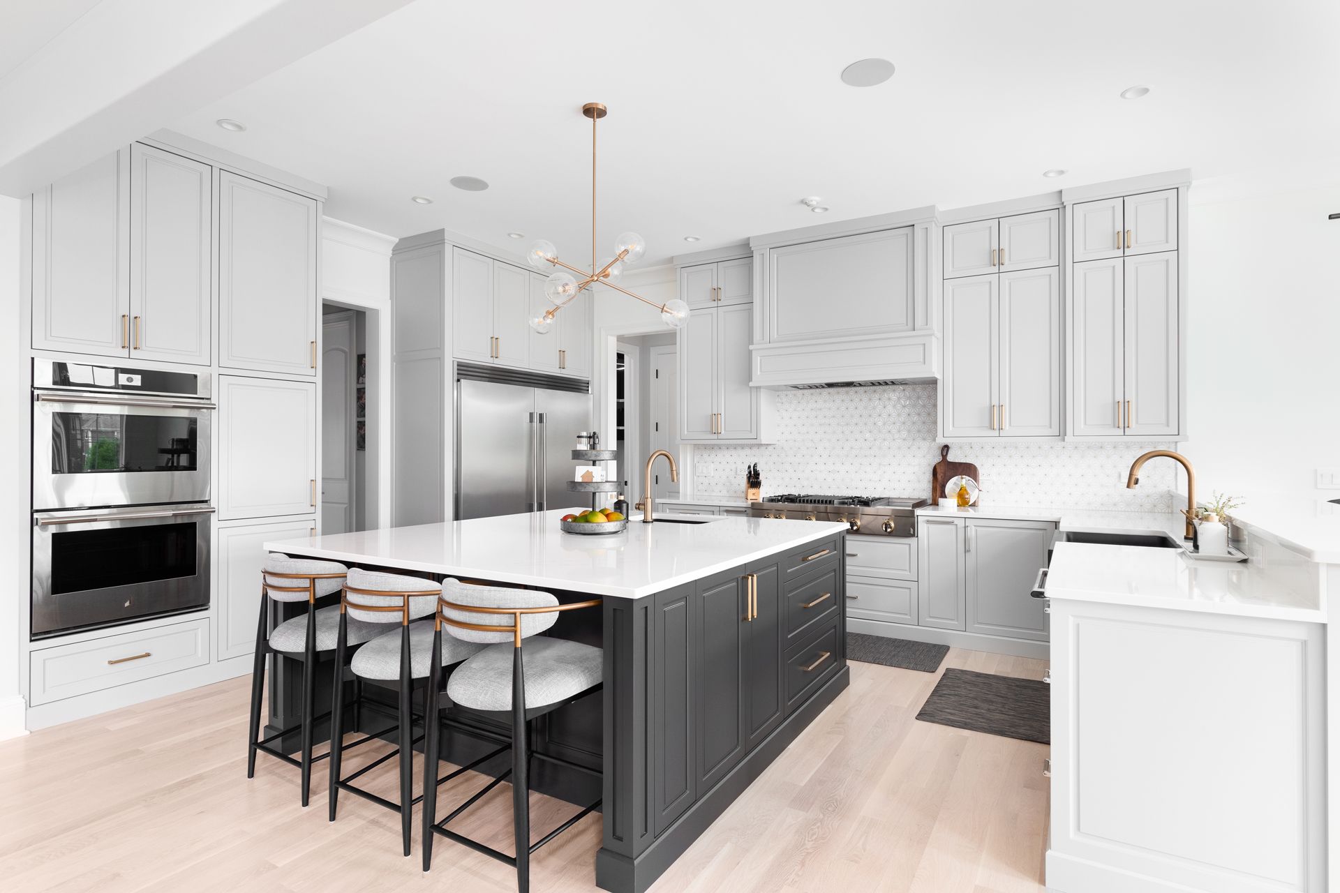 Modern white and gray kitchen with island, stainless steel appliances, and gold accents.