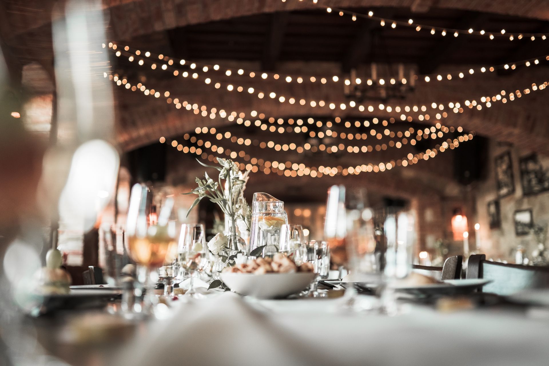 Table set for a celebration with lights strung overhead