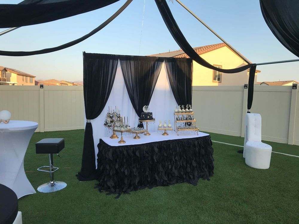 Dessert table with black and white decor set up outdoors on green grass