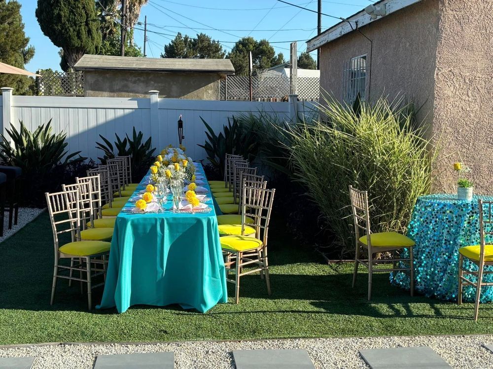Long outdoor table set for a party with teal tablecloth