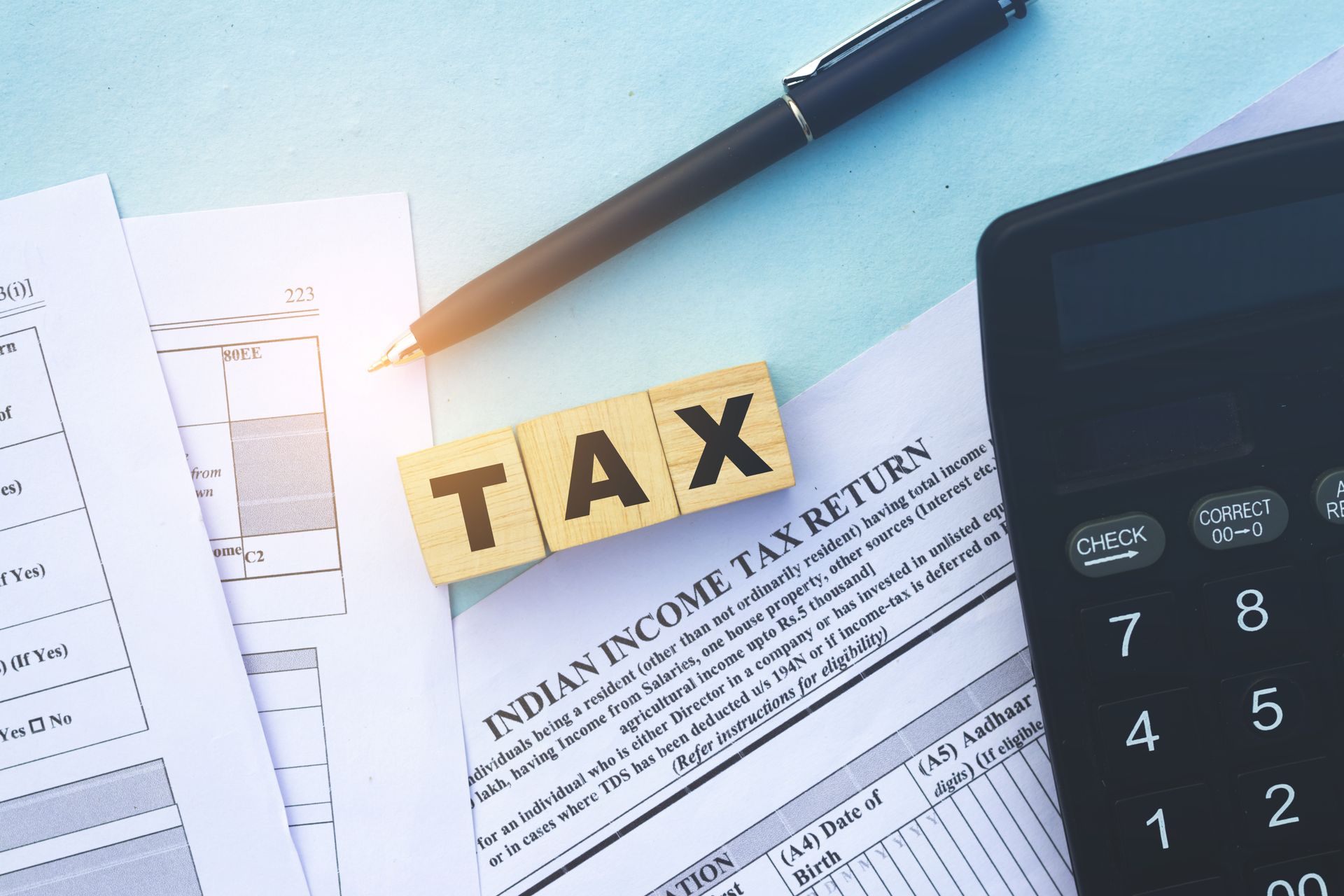 Tax documents with calculator and pen on a desk, highlighted by a TAX label Tax documents with calculator and pen on a desk, highlighted by a TAX label