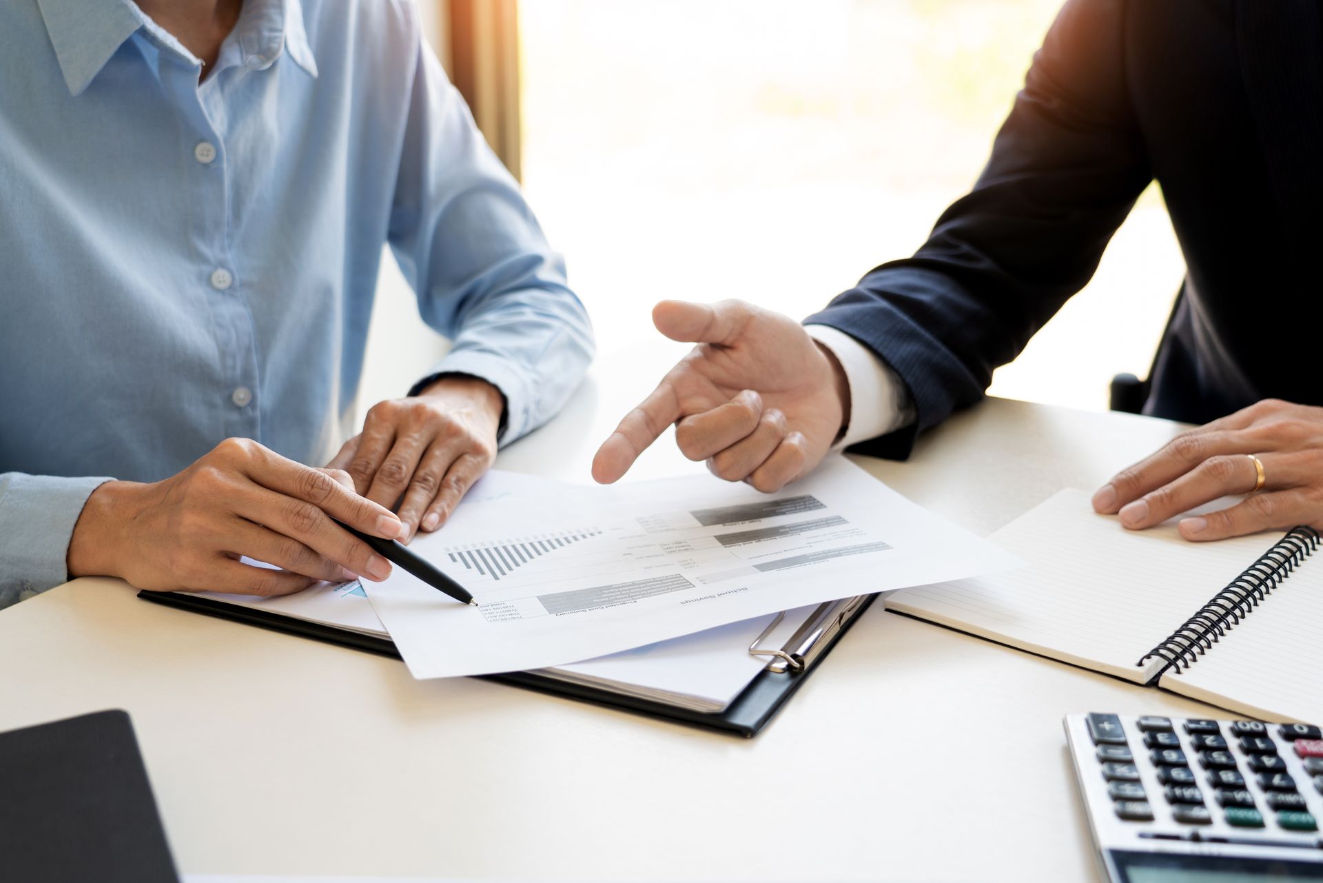 Two people reviewing documents and pointing at paperwork during a meeting at a desk