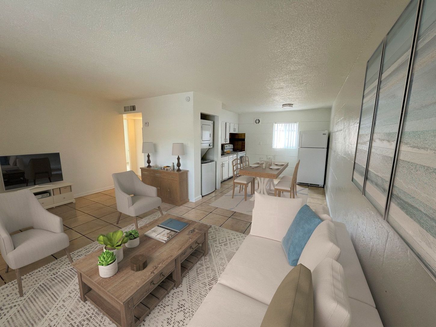 Living room and kitchen with white walls, furniture, and wooden table.