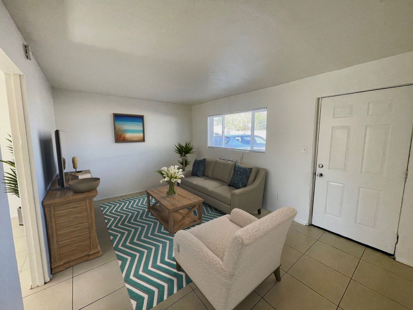 Living room with couch, armchair, and coffee table on a teal chevron rug; artwork on wall.