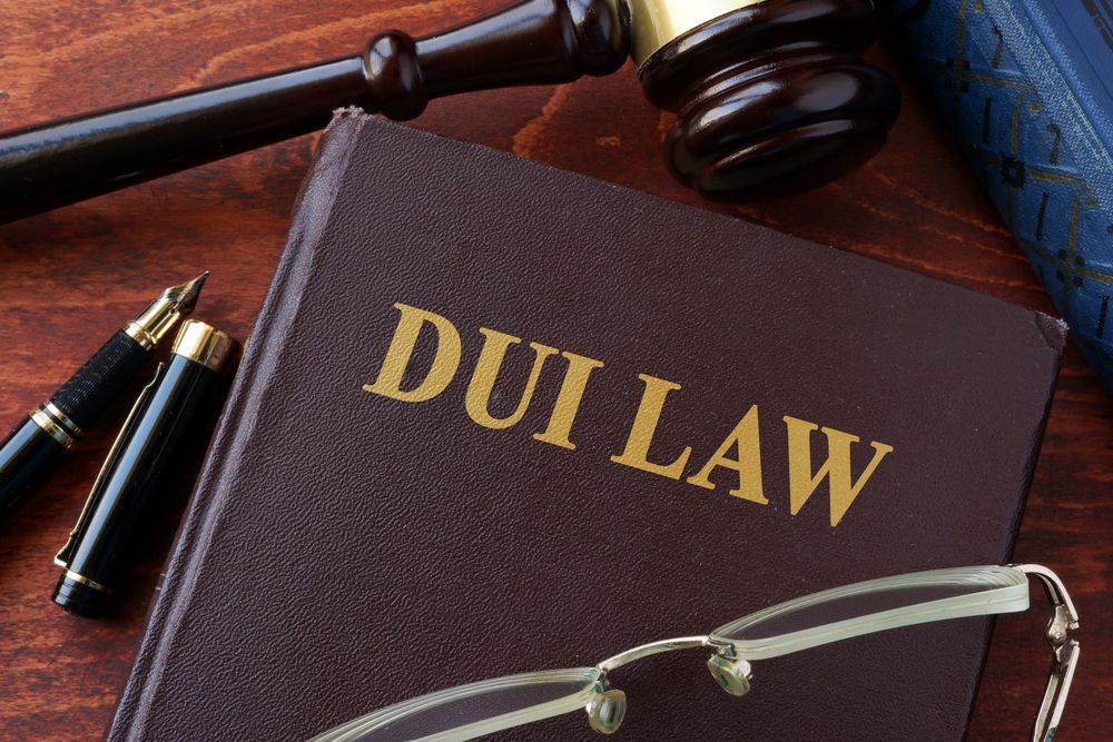A book titled dui law is sitting on a wooden table next to a pen and glasses.