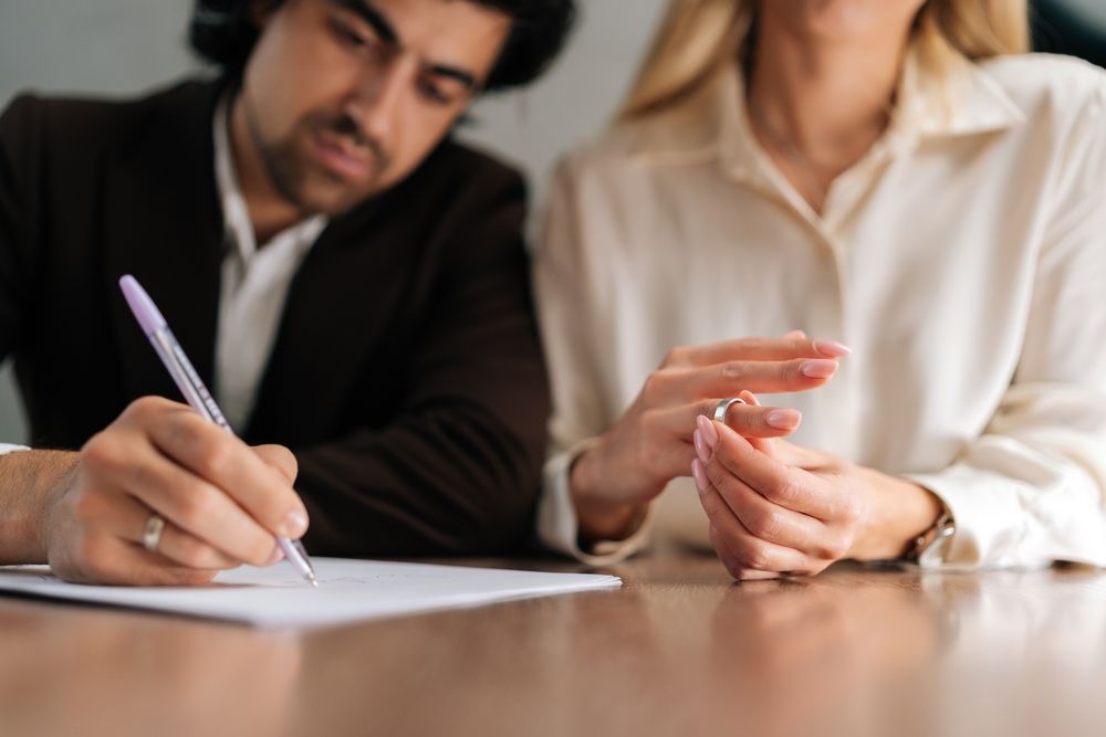 A man and a woman are sitting at a table signing a document.