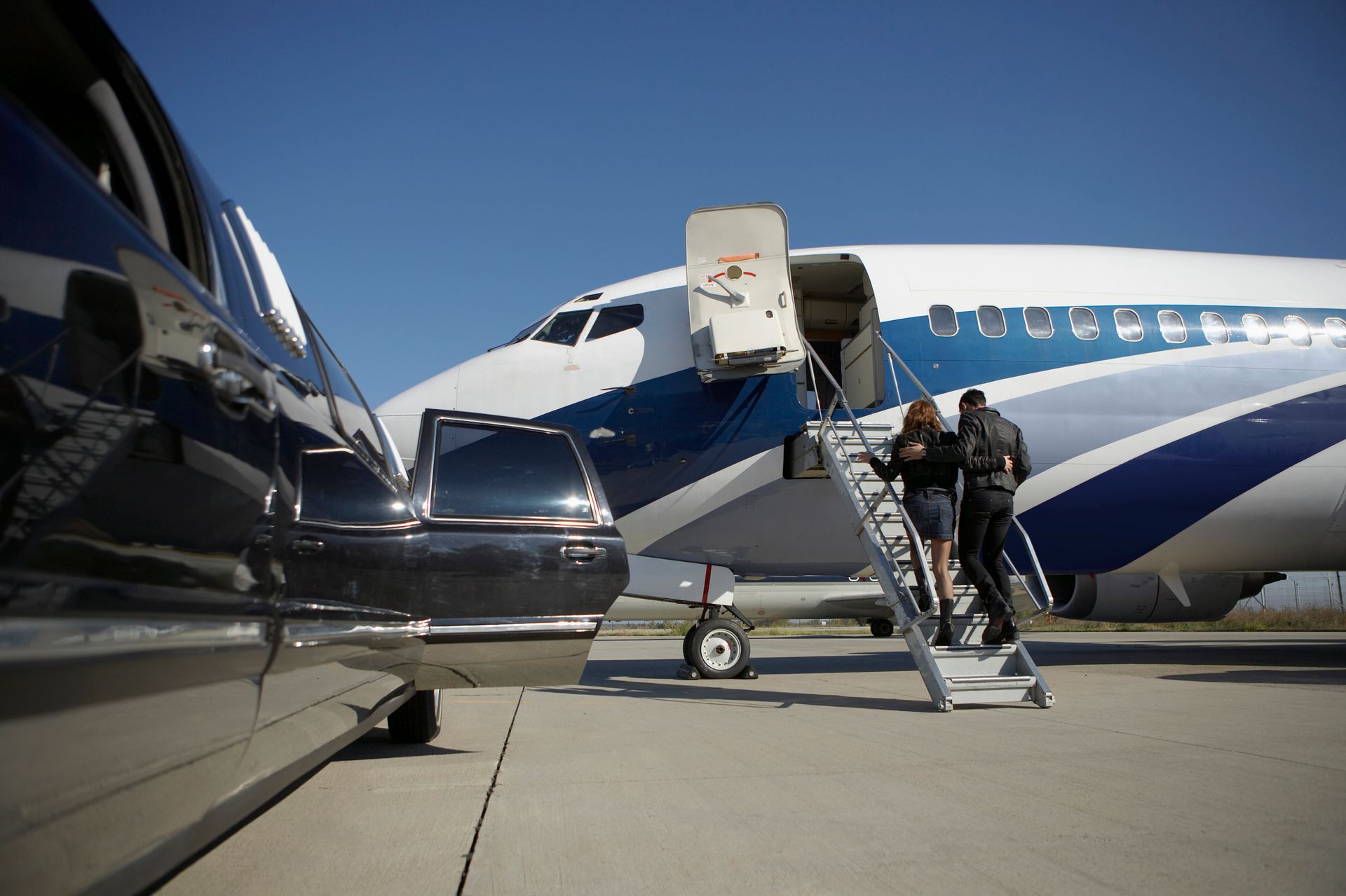 A group of people are boarding a private jet at an airport.