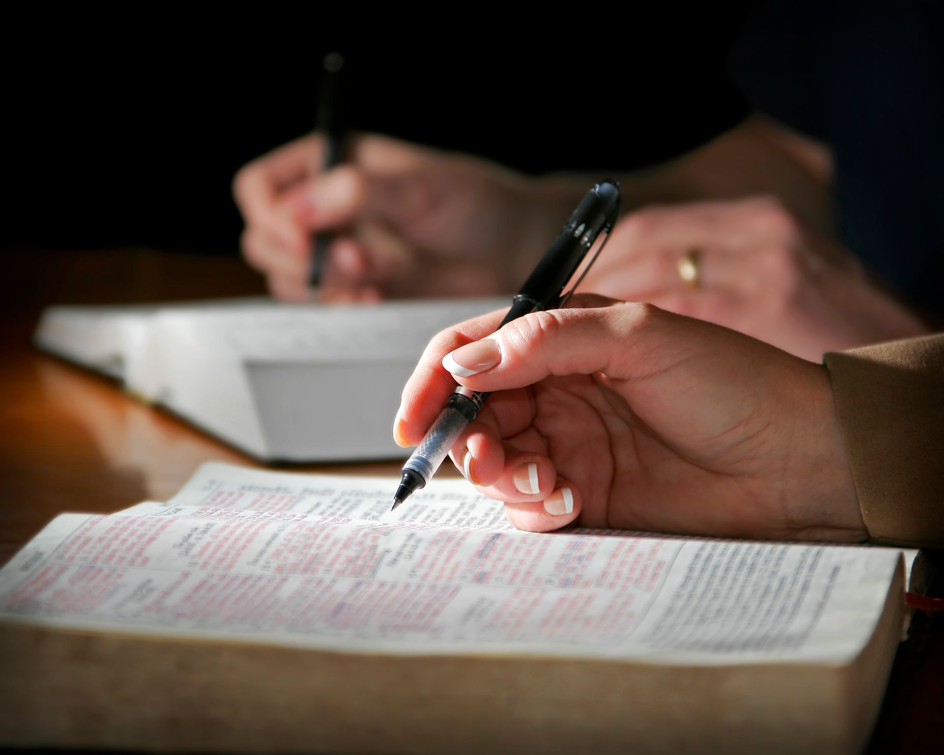 Hands writing notes in notebooks with pens, close-up on a desk