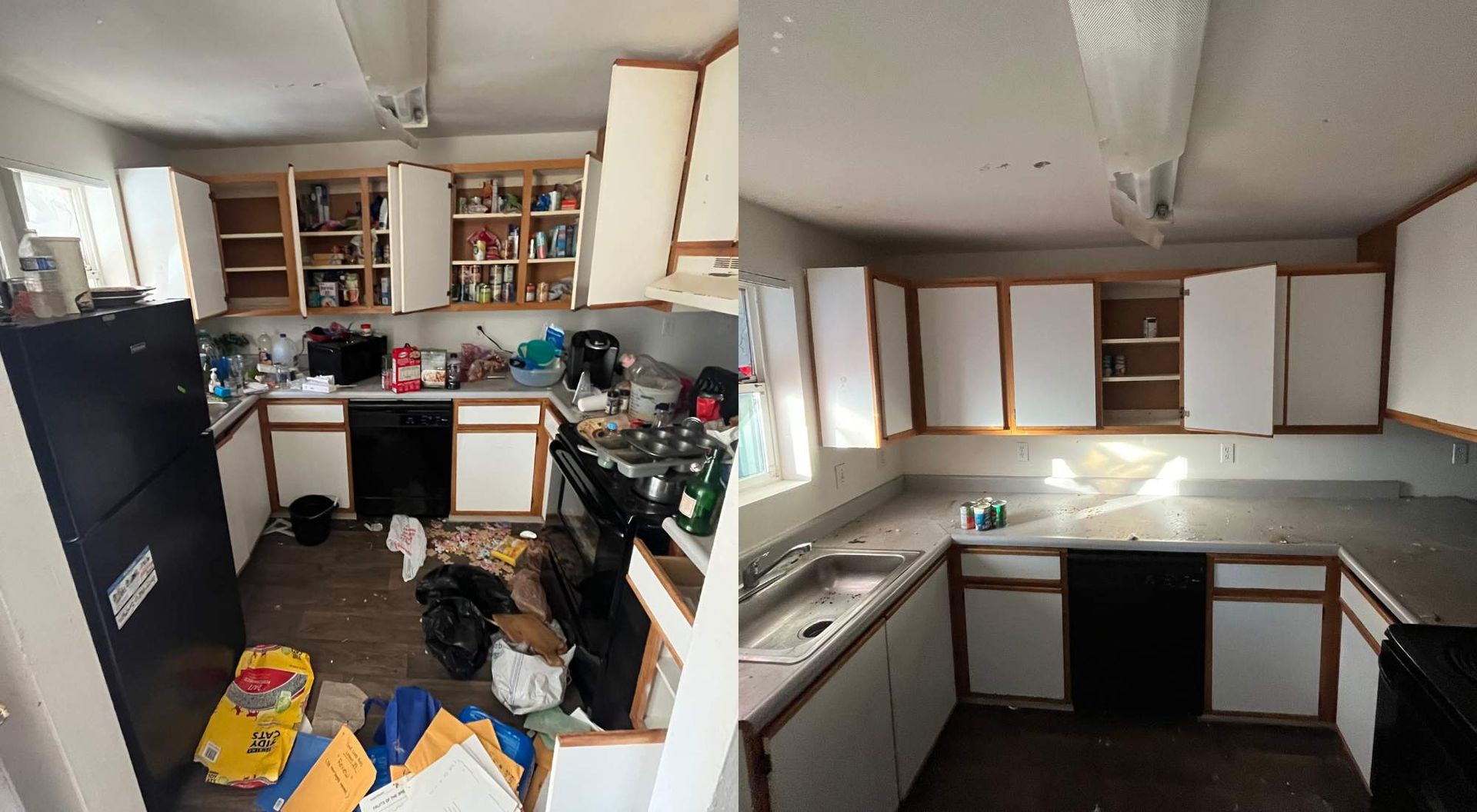 Cluttered kitchen with white cabinets, black refrigerator, and boxes scattered on the floor