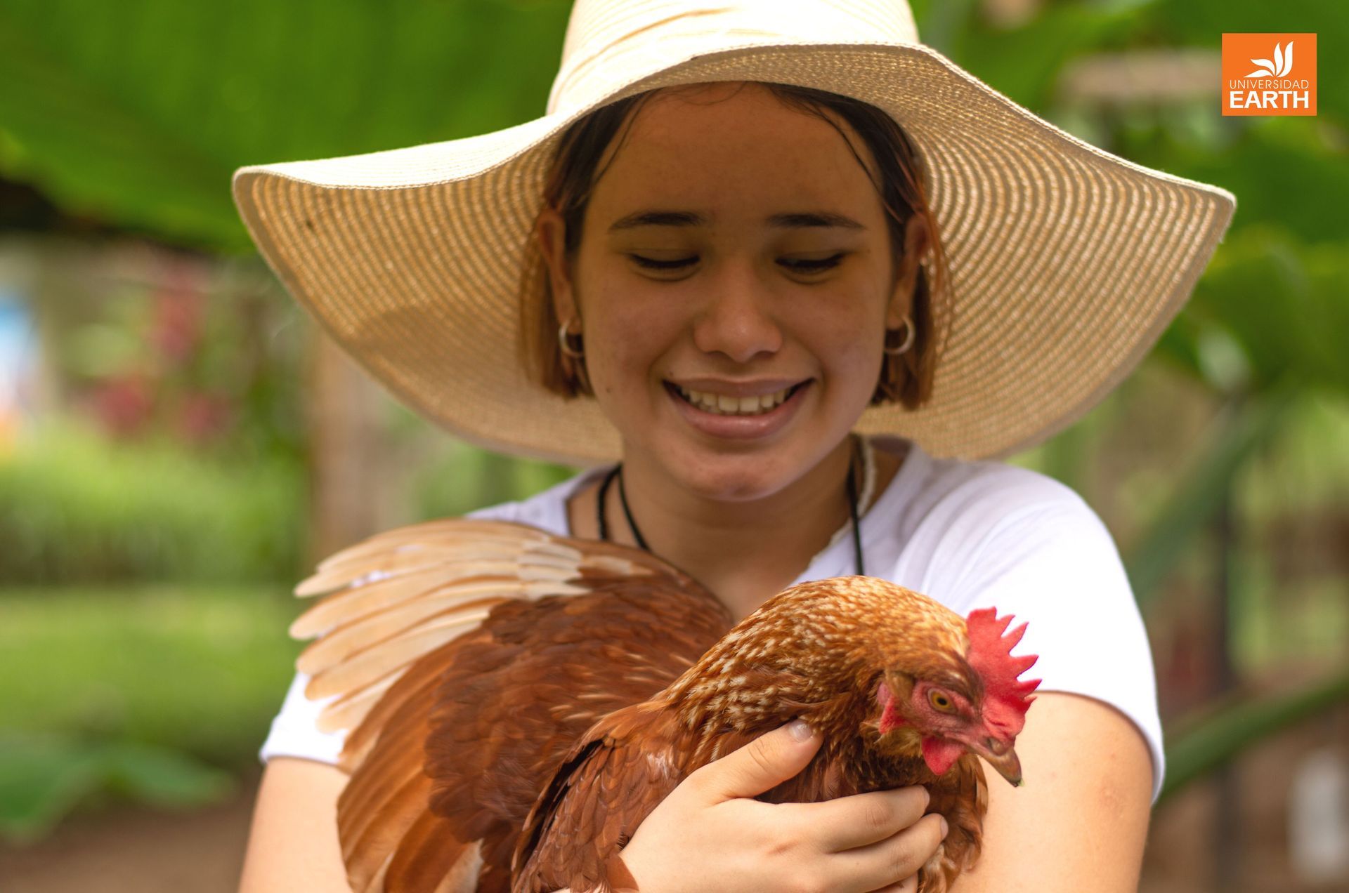 Una mujer con sombrero sostiene un pollo marrón.