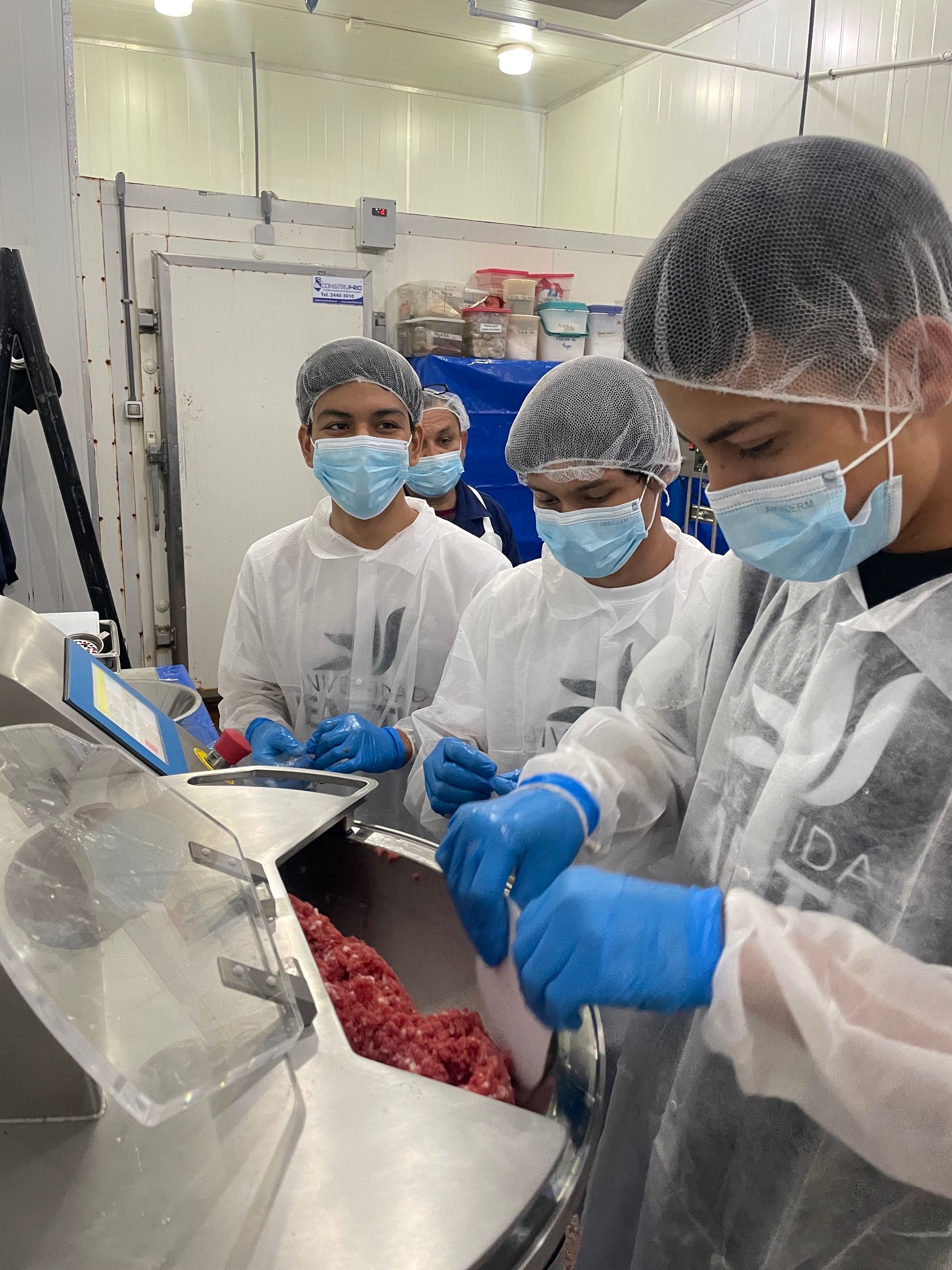 Un grupo de personas con mascarillas y guantes trabajan en una cocina.