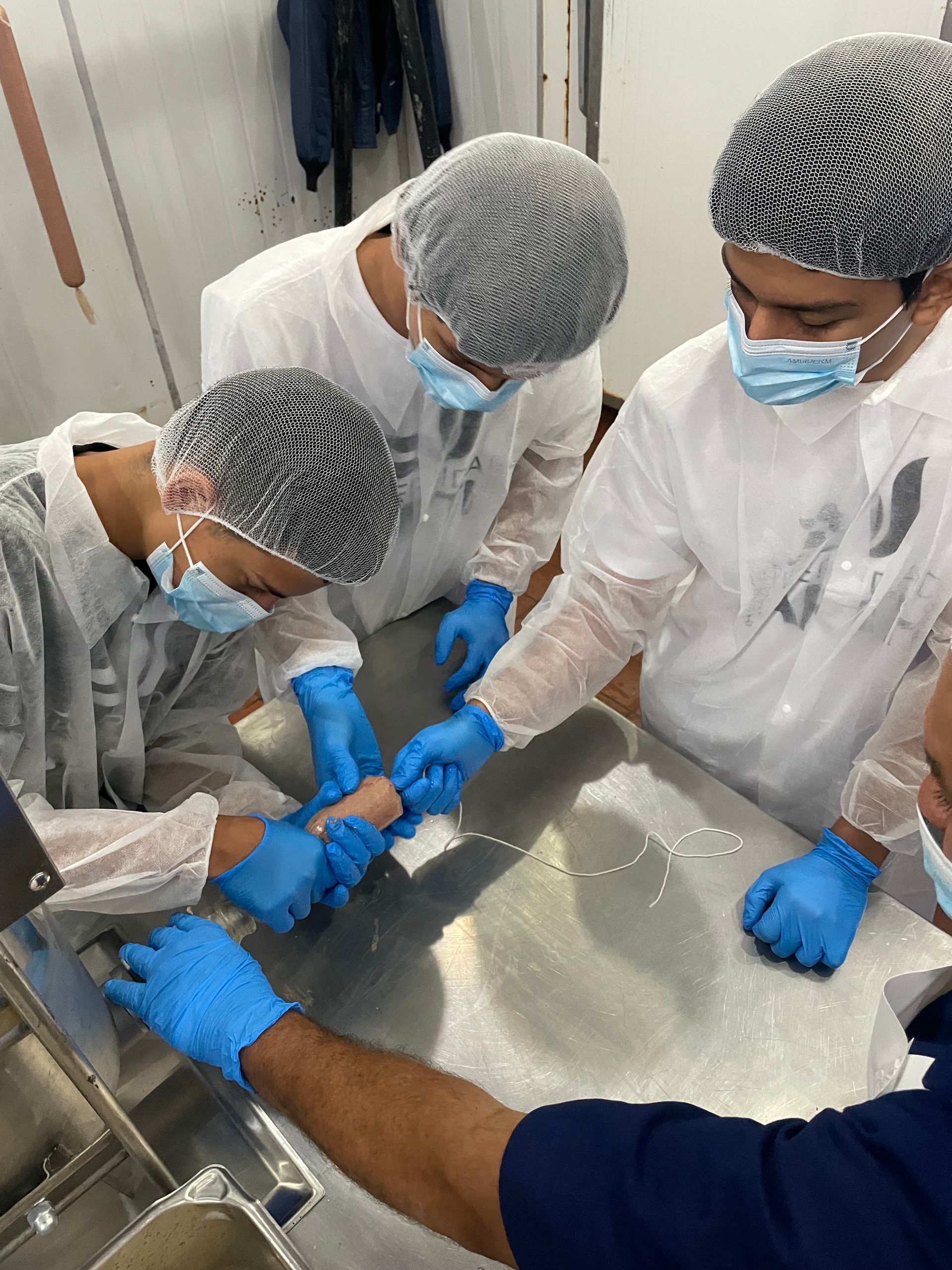 Un grupo de personas con mascarillas y guantes están trabajando en una mesa.