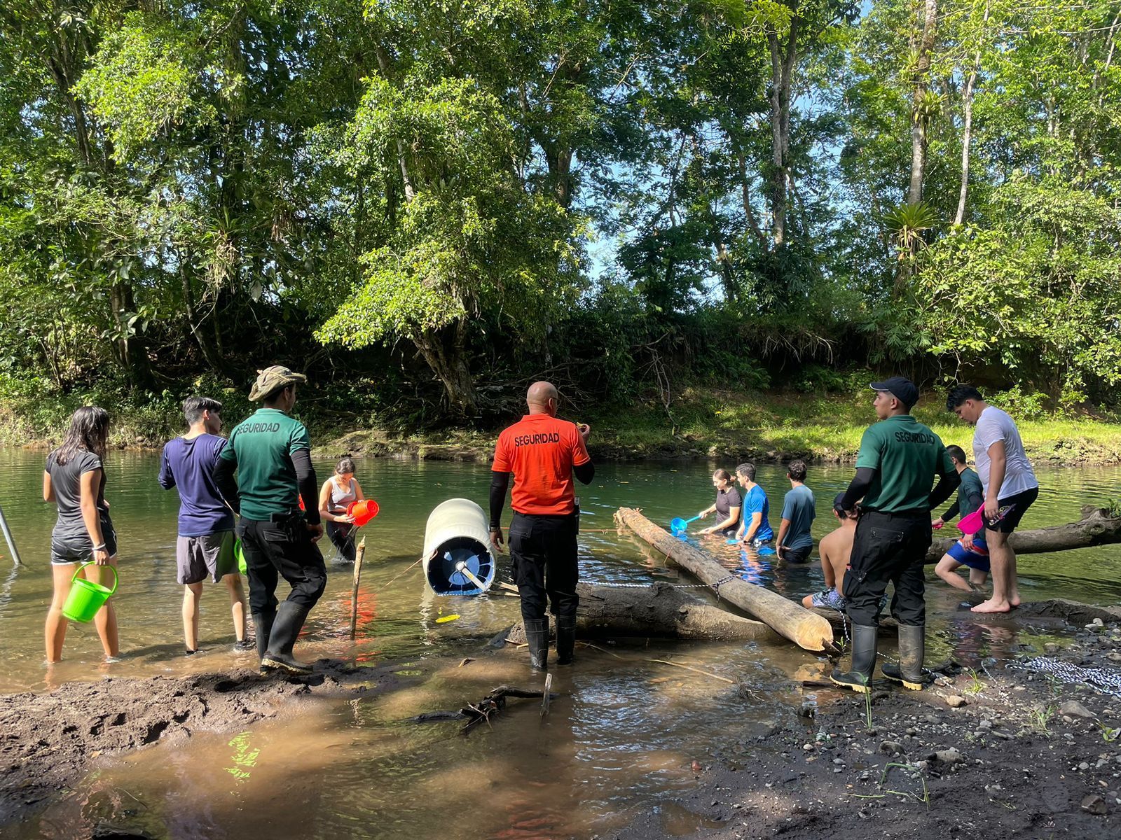 Un grupo de personas están paradas en el agua cerca de un río.