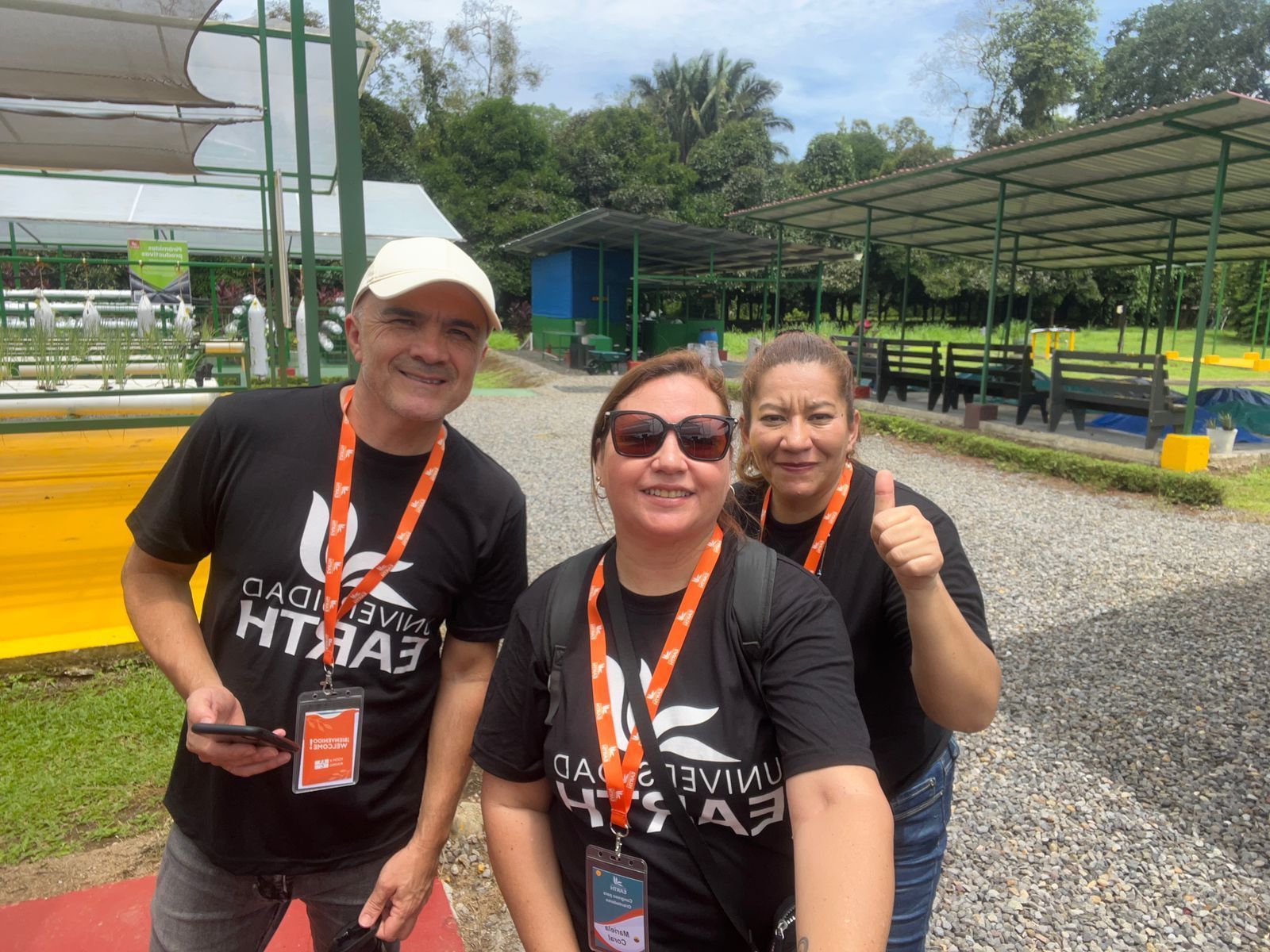 Tres personas sonriendo, vistiendo camisetas negras con la frase 