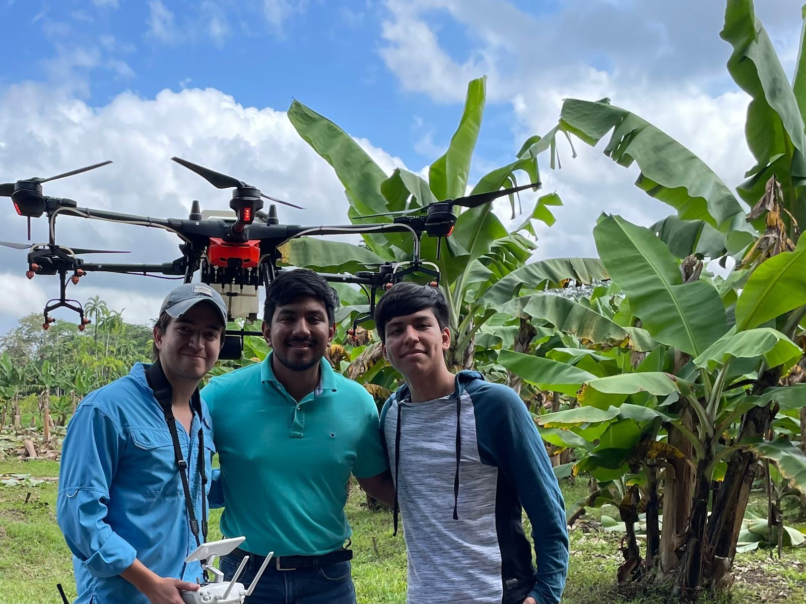 Tres hombres posan para una fotografía con un dron de fondo.