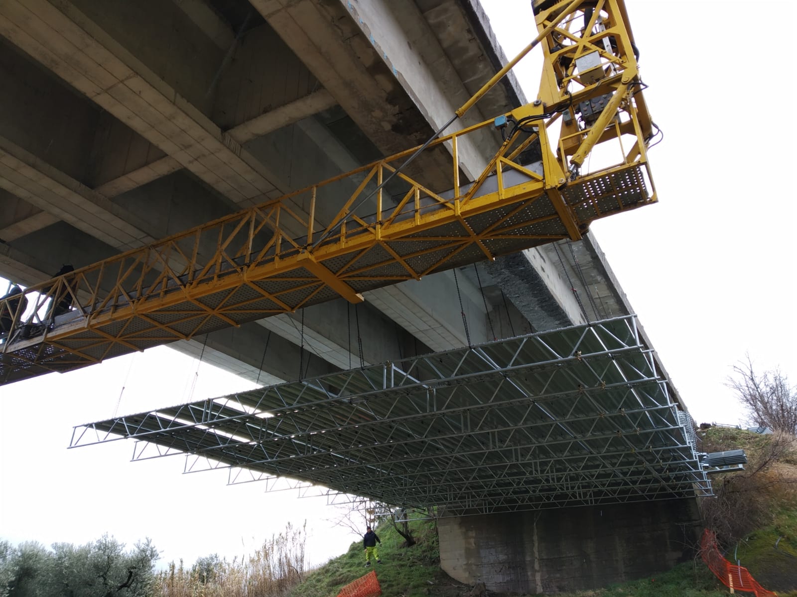 Impalcature gialle sotto un ponte in costruzione, visibili dal basso.