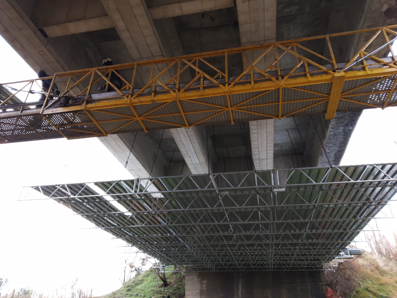 Parte inferiore di un ponte con impalcature e reti di sicurezza installate, presumibilmente per lavori di manutenzione o riparazione.