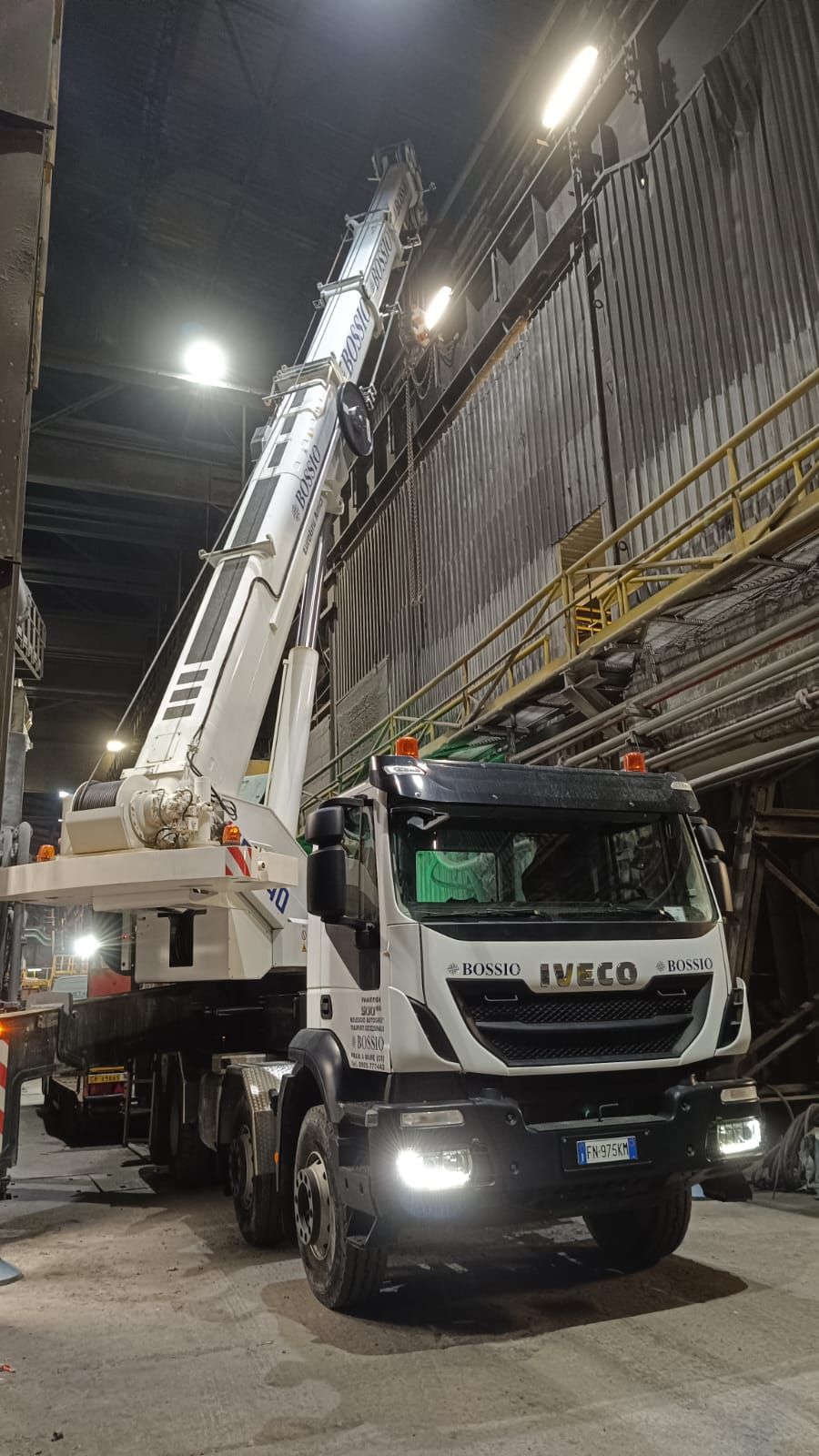 Un camion con una gru sul retro è parcheggiato in un garage di notte.