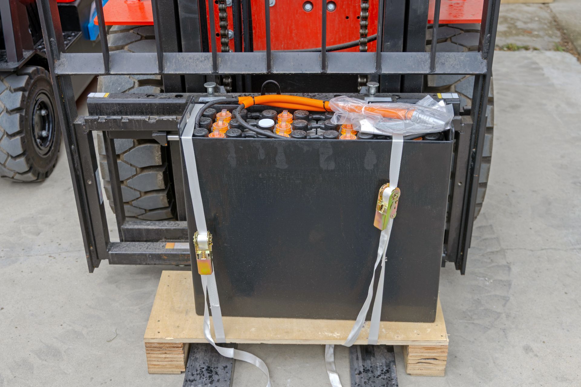 Forklift traction battery with orange cables strapped to a wooden pallet