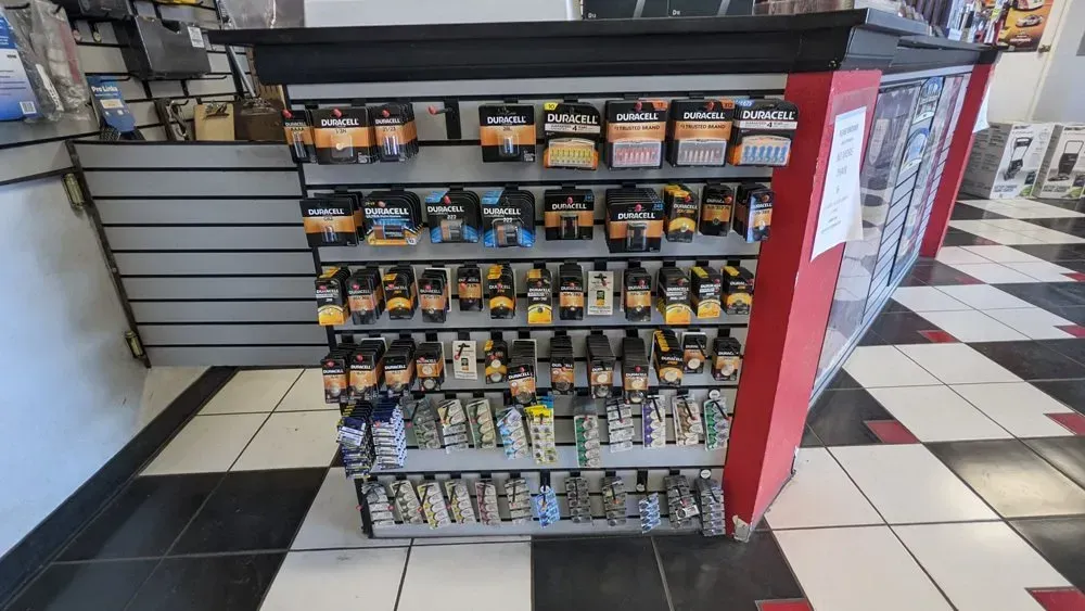 Display of packaged products on shelves in a store, with a red support column and checkerboard flooring.