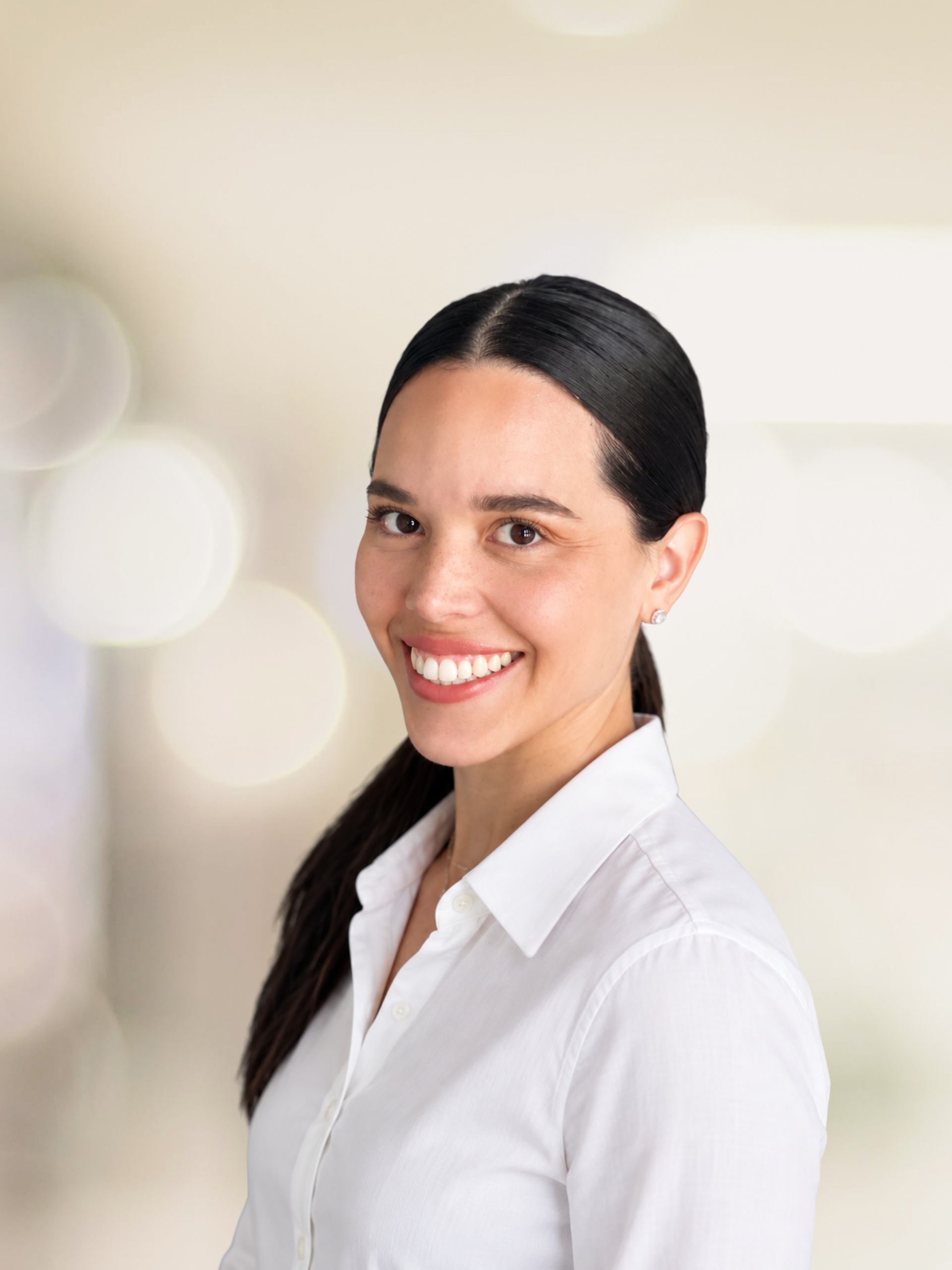 Smiling person in a light blue shirt standing against a bright white background