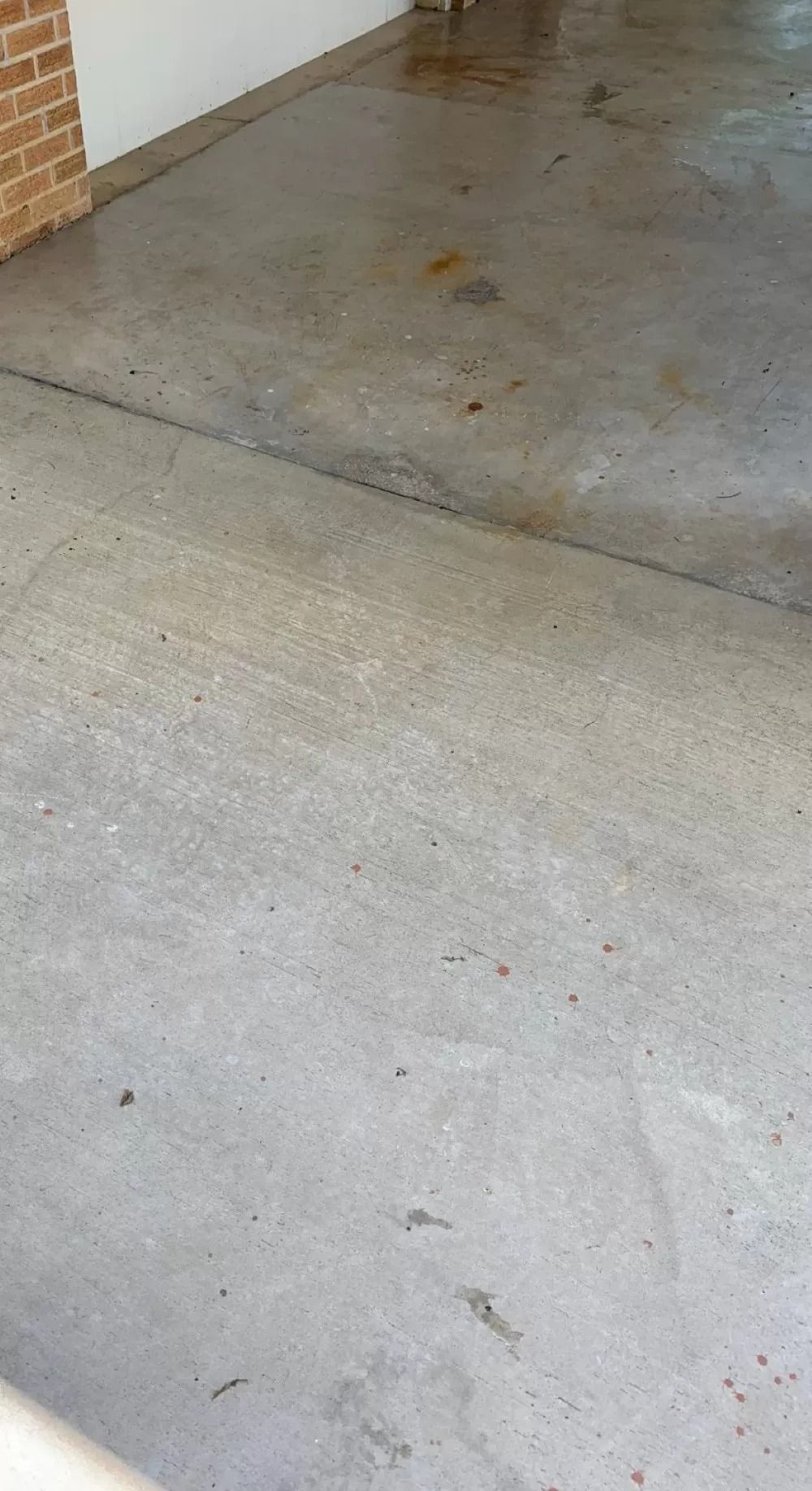 Concrete floor with a dark stain near a brick wall corner