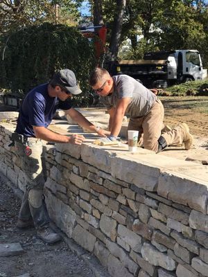 Two men are working on a stone wall.