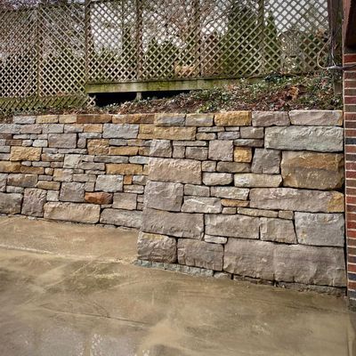 A stone wall with a brick fence in the background