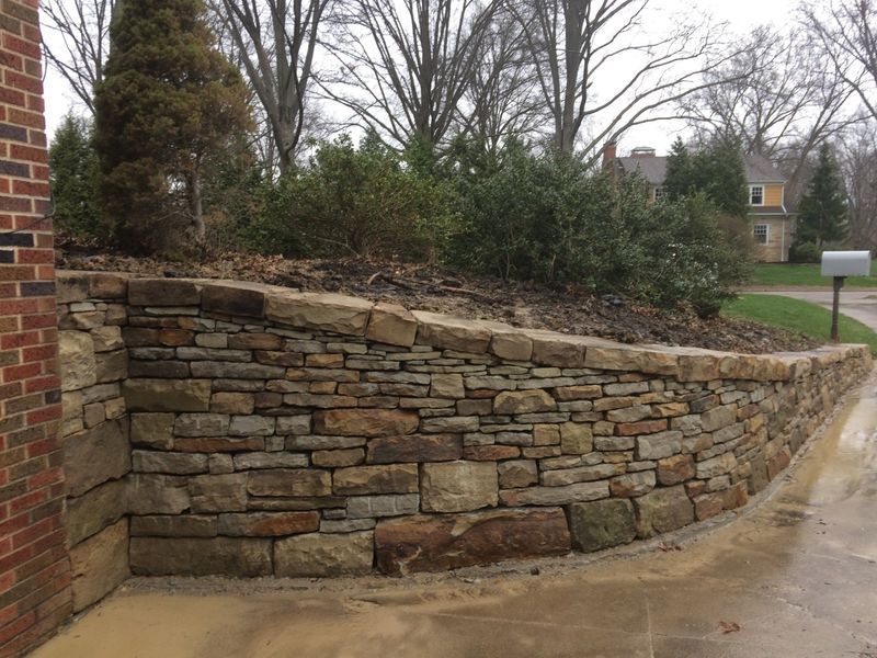 A stone wall with a brick building in the background