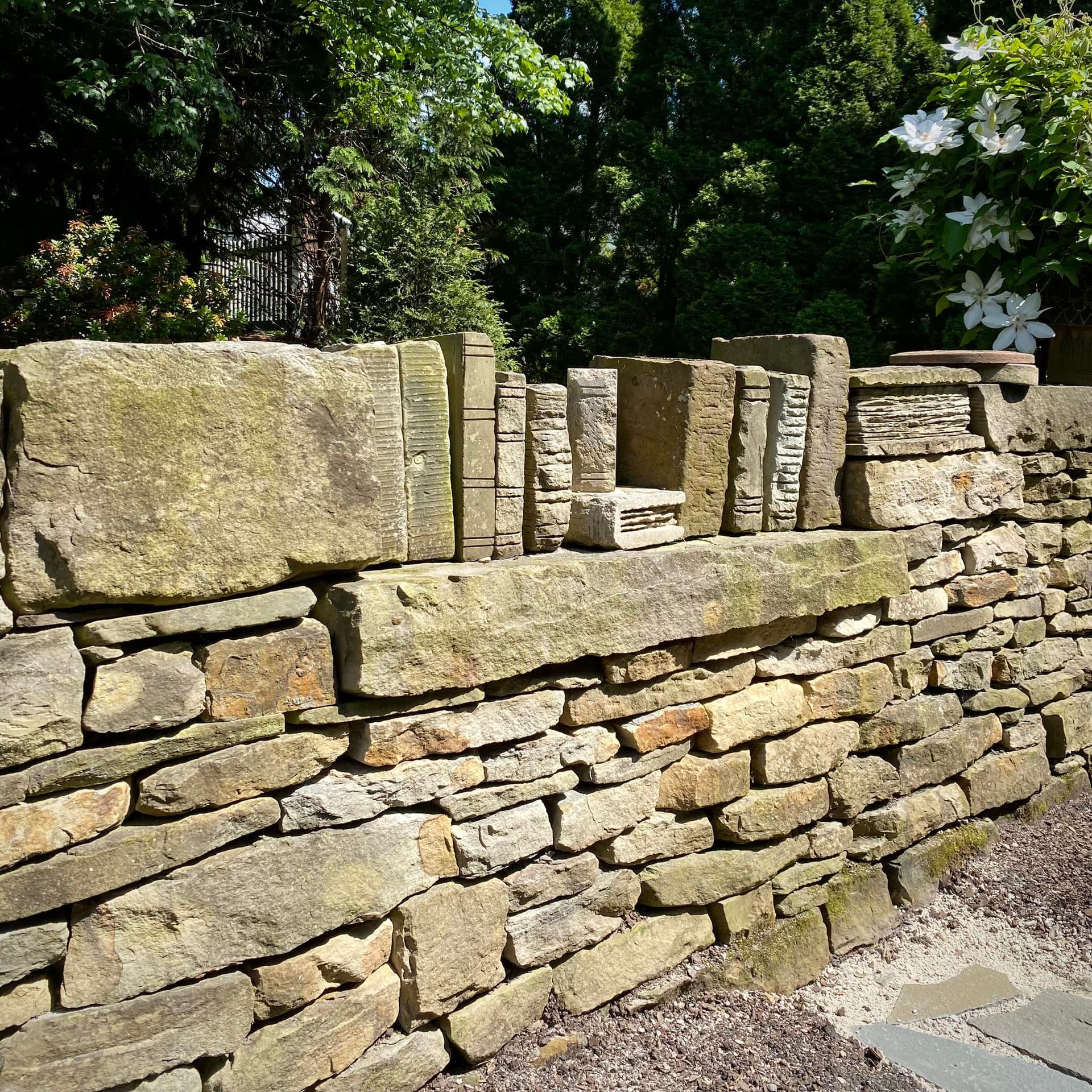 A stone wall is surrounded by trees and flowers