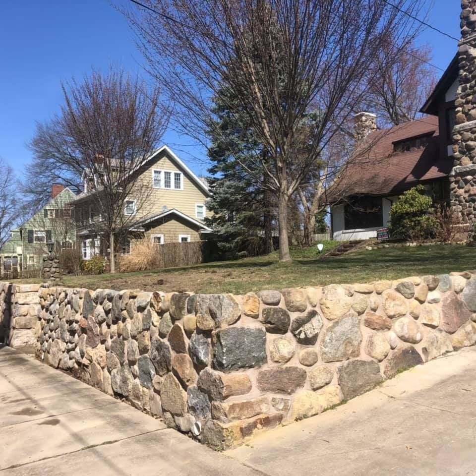 A stone wall with a house in the background