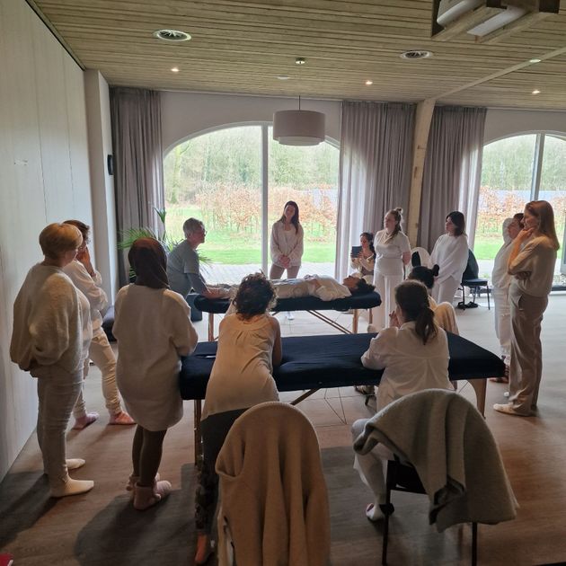 Mensen hadden zich verzameld in een ruimte met massagetafels, waarschijnlijk voor een trainingssessie.