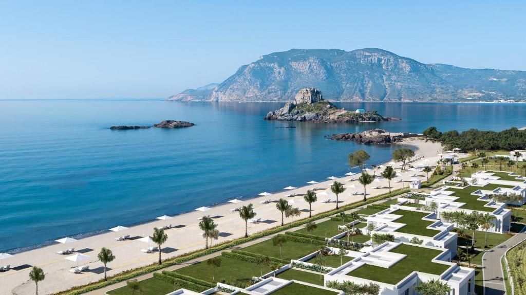 Vedere panoramică al resortului grecesc all-inclusive Ikos Aria. Are ieșire directă la plajă și e în apropierea unui munte.