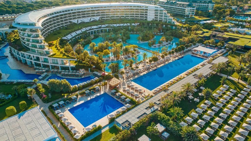 Vedere panormică al resortului all-inclusive Maxx Royal Belek Golf din Antalya, Turcia. Piscine cu apă limpede, vegetație și terenuri de golf.