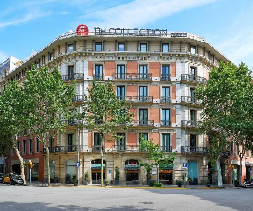 NH Collection Barcelona Podium, fotografiat de pe stradă, cu fațada portocalie și detalii arhitecturale vintage.