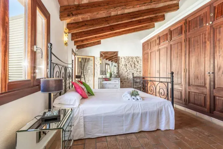 Unul dintre dormitoarele luminoase de la etaj ale vilei Albuqassim din Mallorca. Pe partea dreaptă se observă un dulap de lungimea întregului perete, din lemn masiv.