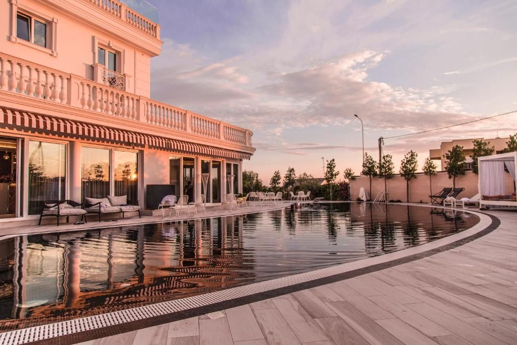 Piscina cu zonă de șezlonguri a hotelului Villa Pascucci din Durrës, surprinsă la apus. Atmosfera este caldă și relaxantă.