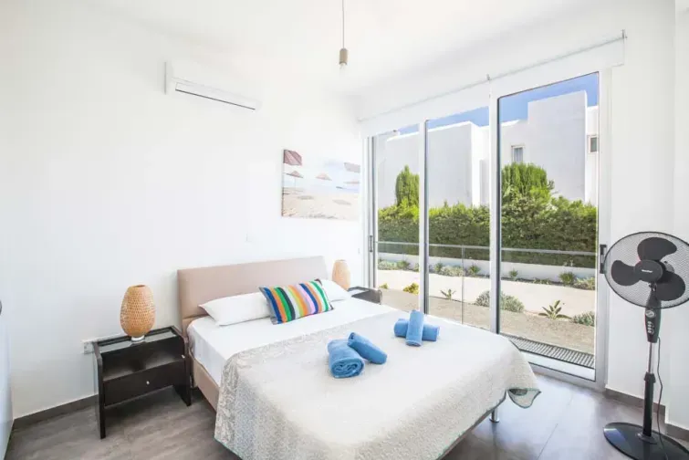 Unul dintre dormitoarele vilei Protaras Greco Villa din Cipru, dotat cu aer condiționat, ventilator și comode. Un dormitor 