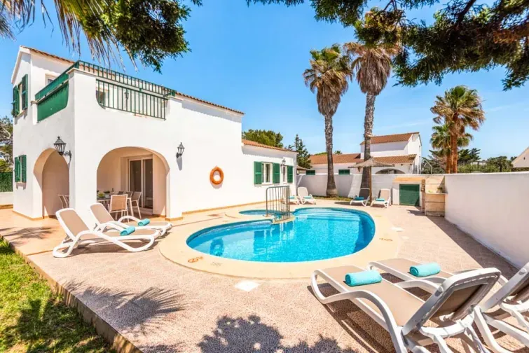 Curtea interioară a vilei Ingrid din Menorca. Are piscină interioară în formă circulară, șezlonguri și mulți palmieri. 