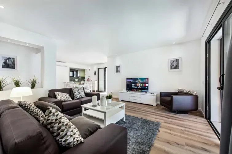 Living-ul deschis al vilei Maria Luisa. Este o sufragerie spațioasă de tip open space, cu un colțar, măsuță de cafea, televizor și balcon care dă spre curtea interioară.