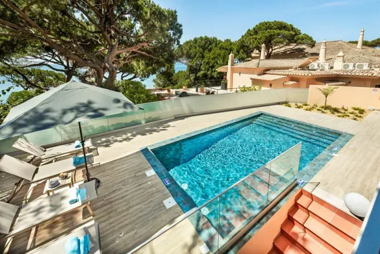 Curtea interioară a vilei Maria Luisa din Algarve. Are șezlonguri, piscină și vedere directă spre vegetație și mare. 